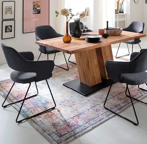 Essgruppe mit massivem Holztisch und sechs grauen Armlehnstühlen auf farbigem Teppich – modernes Esszimmer, gemütliche Einrichtung, hochwertige Essmöbel für stilvolles Wohnen mit Komfort.